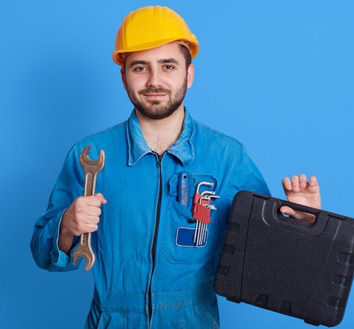 young-handsome-repairman-blue-overall-yellow-helmet-holding-toolbox-wrench-bearded-plumber-standing-isolated-color-wall-man-working-holds-toolbox-with-instrument-min